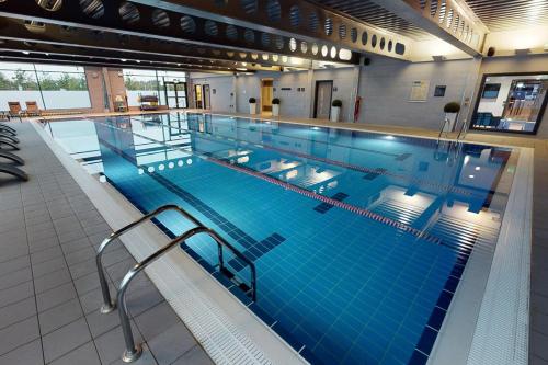 a large indoor swimming pool with blue water at Village Hotel Aberdeen in Aberdeen