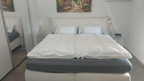 - un lit avec des draps et des oreillers blancs dans l'établissement Modernes Apartment in Minden am Hauptbahnhof, à Minden
