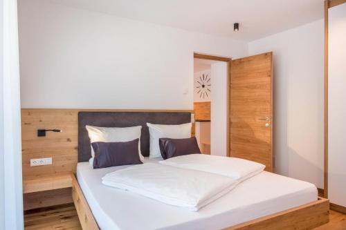 Schlafzimmer mit einem weißen Bett mit einem Kopfteil aus Holz in der Unterkunft Luisl Hof - Apartment Vitis in Girlan