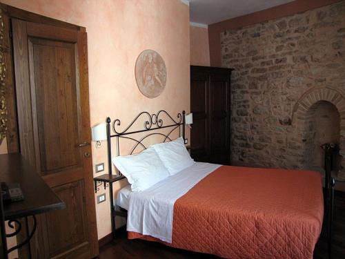 1 dormitorio con cama y pared de ladrillo en La Luna nel Borgo en Spello