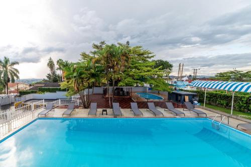 uma grande piscina com cadeiras e árvores em Afro Park Hotel em Kampala