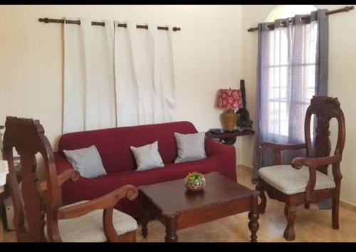 a living room with a red couch and a table at Apartamento JM. in San Felipe de Puerto Plata