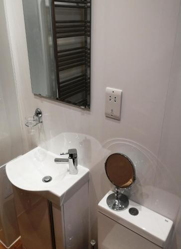 a white bathroom with a sink and a mirror at Cumberland Hotel in Edinburgh