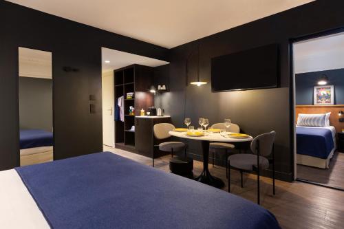 a hotel room with a bed and a table with chairs at RockyPop Grenoble Appartements in Grenoble