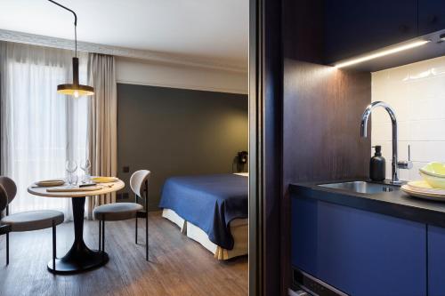 a room with a bed and a table and a sink at RockyPop Grenoble Appartements in Grenoble