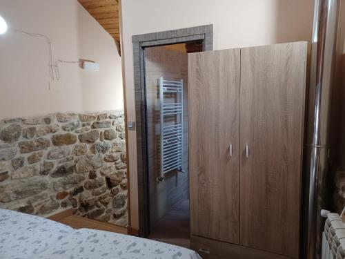 1 dormitorio con armario de madera y pared de piedra en Buscando el Norte, en Cabrillanes