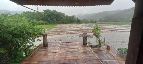 a wooden bridge over a river with a rice field at Chinopuu Hut Homestay Muangkong ชิโนปู ฮัท โฮมสเตย์ เมืองคอง เชียงดาว in Mueang Khong