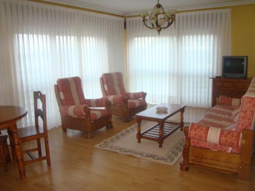 a living room with chairs and a table and a tv at Apartamentos Peña Mar in Castropol