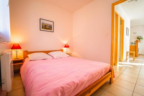 - une chambre avec un grand lit et des draps roses dans l'établissement Les Chalets de la Vallée du Bés, à Saint-Juéry