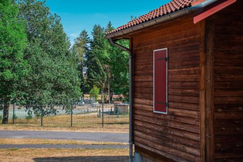 a wooden building with a red door on a park at Les Chalets de la Truyère in Le Malzieu-Ville