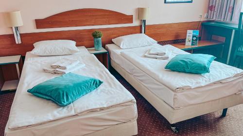 two beds in a hotel room with towels on them at Aqua Hotel in Polkowice