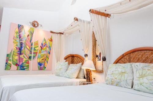 two beds in a bedroom with white walls at Monyoli Hotel & Boutique in Acapulco