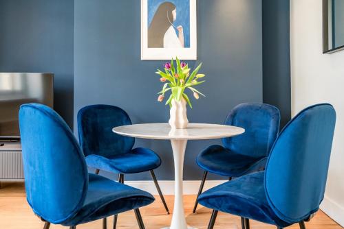 einen Tisch mit blauen Stühlen und eine Vase mit Blumen in der Unterkunft Be London - The Covent Garden Residences in London