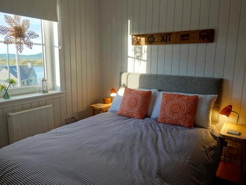 a bedroom with a bed with orange pillows and a window at Hona in Mangersta