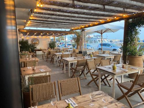 a restaurant with wooden tables and chairs and lights at Les Vagues in Saintes-Maries-de-la-Mer