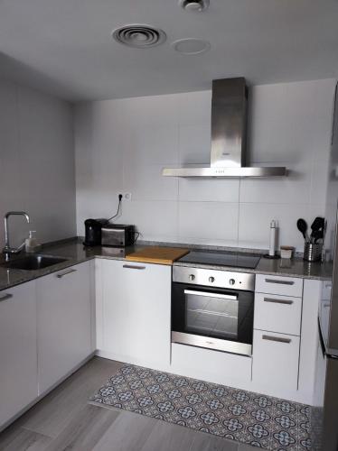 a kitchen with white cabinets and a stove top oven at ROQUES DAURADES III - JARDIN PRIVADO in L'Ametlla de Mar
