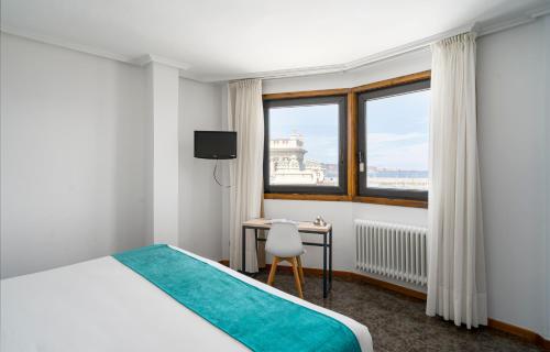 1 dormitorio con cama, escritorio y ventana en Hotel Alda Pasaje, en Gijón