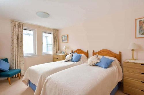 a bedroom with two beds and a blue chair at Links View, Golf Place in St. Andrews