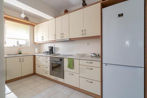 een keuken met witte kasten en een koelkast bij Casa d'Arte in Vrahati