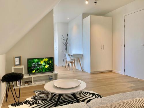 a living room with a couch and a tv and a table at Sleutelhuys in Tielt