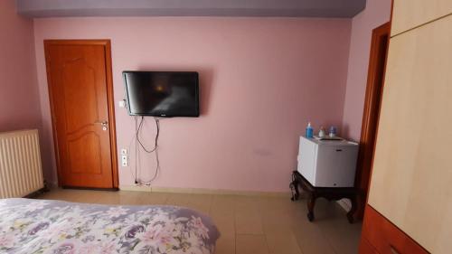 a bedroom with a bed and a tv on the wall at IOANNIS - Room with balcony near Limnopula in Gavrolímni