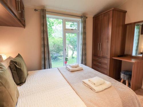 a bedroom with a bed with two towels on it at Tiggywinkle Beck Lodge in Windermere