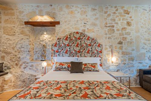 ein Schlafzimmer mit einem Bett mit einer Steinmauer in der Unterkunft Castelvecchio Suites in Rethymno