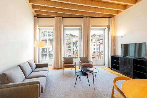 uma sala de estar com um sofá e cadeiras e uma televisão em Mouzinho Village River em Porto
