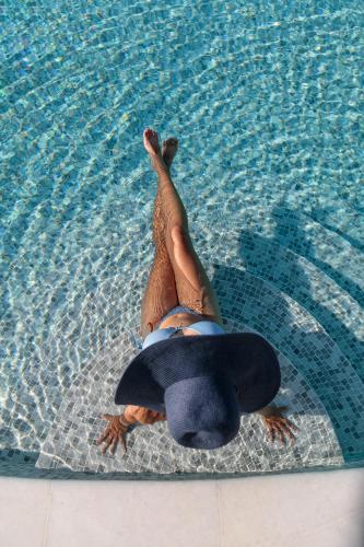 a person in a swimming pool with a surfboard in the water at Cosmos Hotel in Plaka