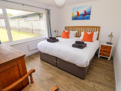 a bedroom with a bed with orange pillows and a window at Chalfonts Cottage in Haverfordwest