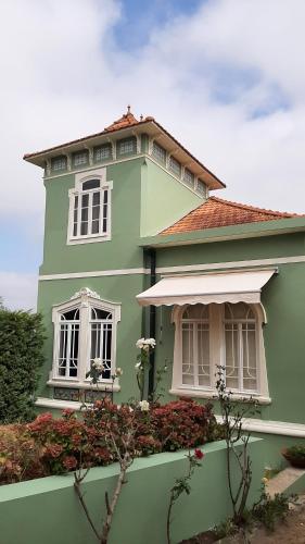 a green house with white windows and flowers at Casa Vila Palmeira in Fermelã