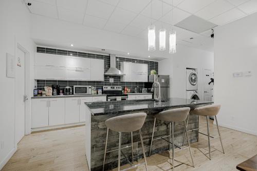a white kitchen with a counter and stools at HoMa Homestay Hostal by Olympic Stadium! in Montréal