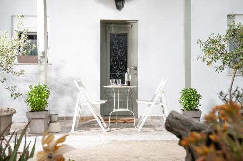 a porch with two white chairs and a table at Agrikia tis Vasilikis in Ormília