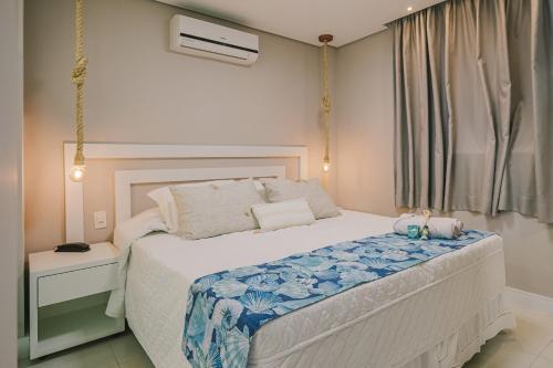 a bedroom with a bed with a blue and white blanket at Hotel Sete Ilhas in Florianópolis