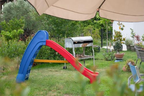 a slide in a yard with an umbrella at Agrikia tis Vasilikis in Ormília