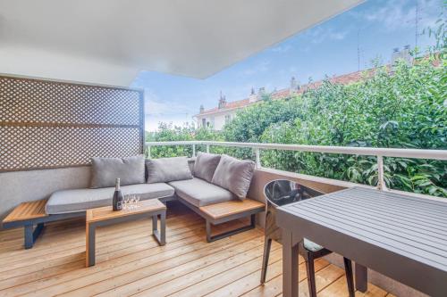 a patio with a couch and tables on a balcony at Appartement Thiers - Welkeys in Antibes