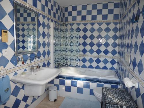 La salle de bains bleue et blanche est pourvue d'un lavabo et d'une baignoire. dans l'établissement Chambre d'Hotes La Brunetière, à Gréoux-les-Bains