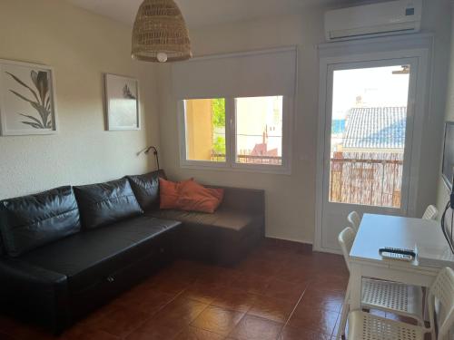 salon z czarną kanapą i dwoma oknami w obiekcie Relaxing vacation at the beach w Maladze