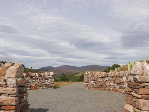 a stone wall with mountains in the background at Ceol-na-Mara in Berriedale