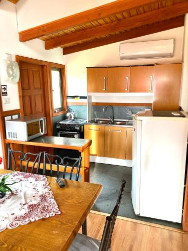 a kitchen with a table and a white refrigerator at Cabañas El Galo in Panguipulli