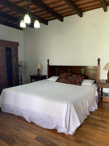 a bedroom with a large white bed with two tables at Villa de Antaño in Antigua Guatemala