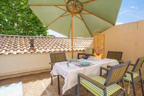 une table avec des chaises et un parasol sur une terrasse dans l'établissement Appartement Pompidou - Welkeys, à La Seyne-sur-Mer