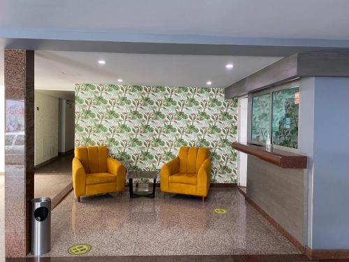 two orange chairs and a table in a lobby at Hotel Menara in Mexico City