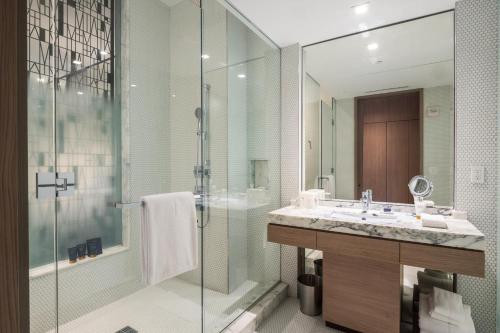 La salle de bains est pourvue d'un lavabo et d'une douche en verre. dans l'établissement Suites at SLS Lux Brickell managed by CE, à Miami