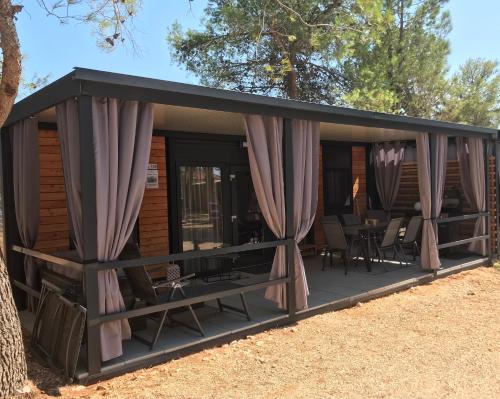 a screened in porch with curtains on it at H&S Mobile Home in Privlaka