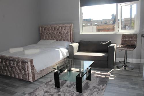 a bedroom with a bed and a couch and a chair at Lovely Central Luton Studio - Ideal for Airport! in Luton