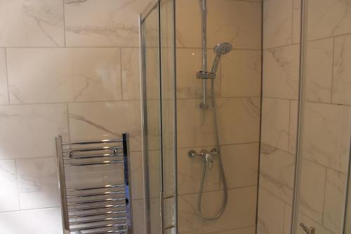 a shower with a glass door in a bathroom at Lovely Central Luton Studio - Ideal for Airport! in Luton