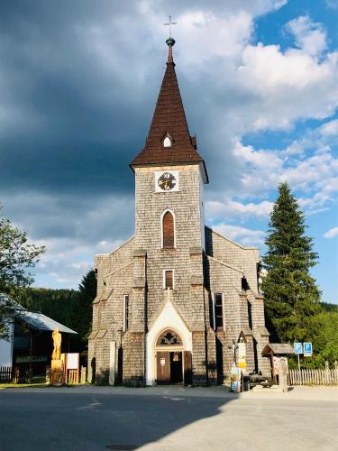 a church with a tower with a clock on it at Strunzova Pila - apartmány s wellness 2,06 a 3,03 in Kvilda