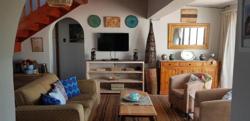 a living room with two chairs and a tv at StarFish Accommodation in Struisbaai