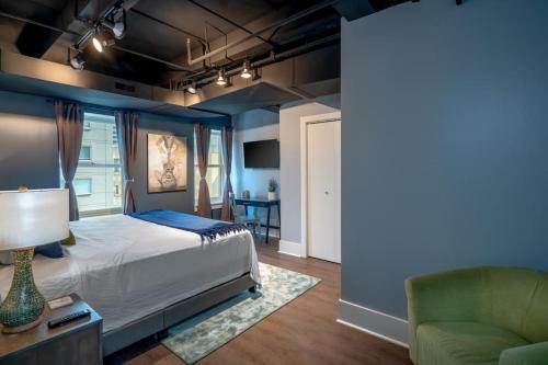 a bedroom with a bed and a green chair at Contemporary flat at The Maddox in Nashville